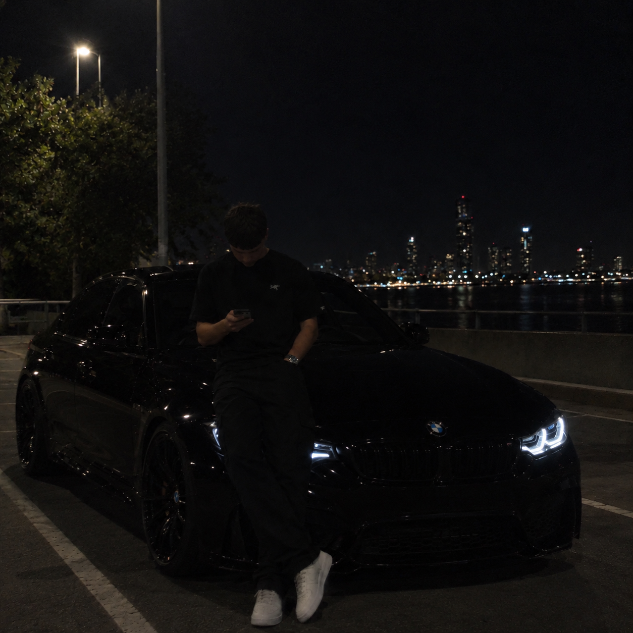 Cody Beale with a black BMW by the waterfront at night